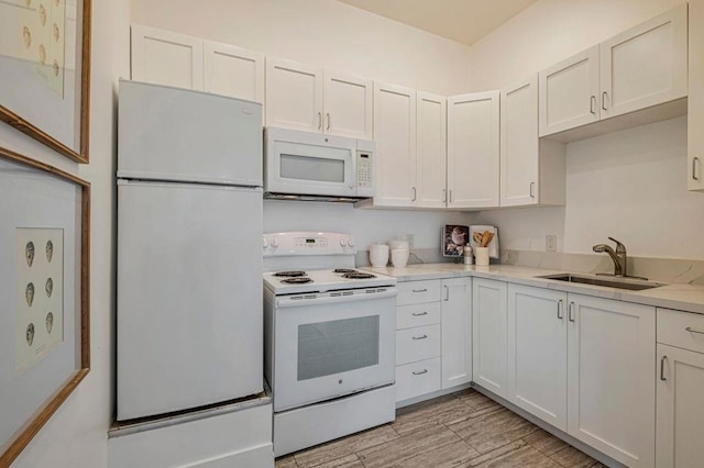 kitchen featuring white cabinetry, sink, white appliances, and light stone counters