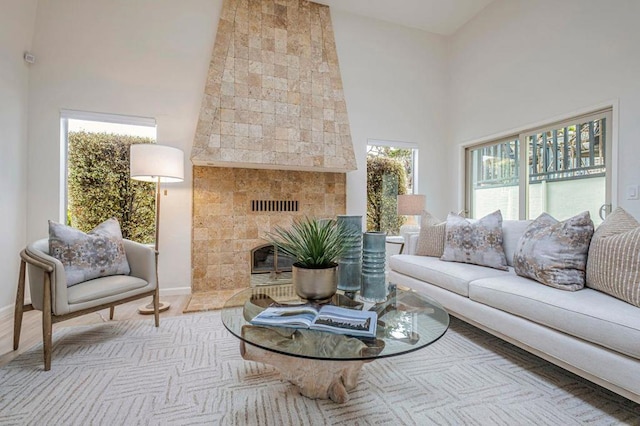 living room featuring a tiled fireplace, light hardwood / wood-style floors, and a high ceiling