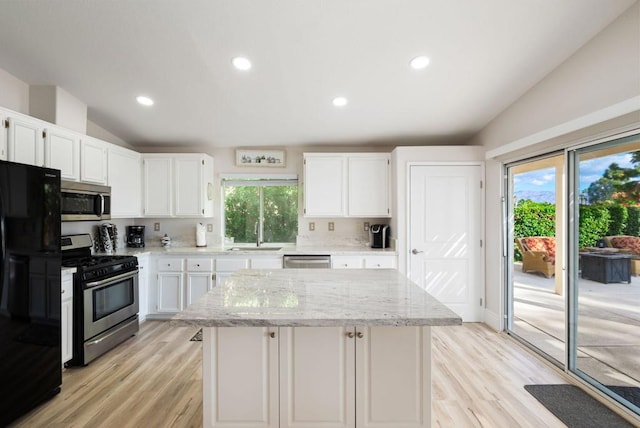 kitchen featuring white cabinetry, light hardwood / wood-style flooring, stainless steel appliances, and vaulted ceiling