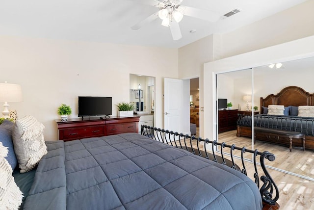 bedroom with ceiling fan, light hardwood / wood-style floors, a high ceiling, and a closet