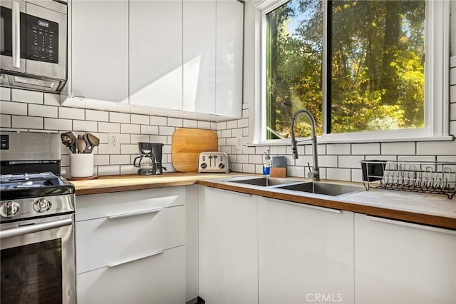 kitchen featuring wood counters, a healthy amount of sunlight, sink, and appliances with stainless steel finishes