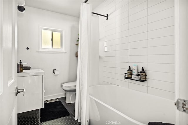 full bathroom with tile patterned floors, shower / bath combo with shower curtain, vanity, and toilet