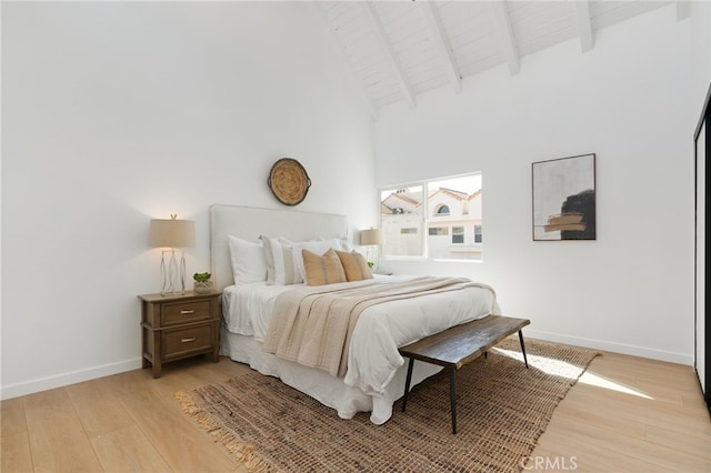 bedroom featuring wooden ceiling, light wood-type flooring, beam ceiling, and a high ceiling