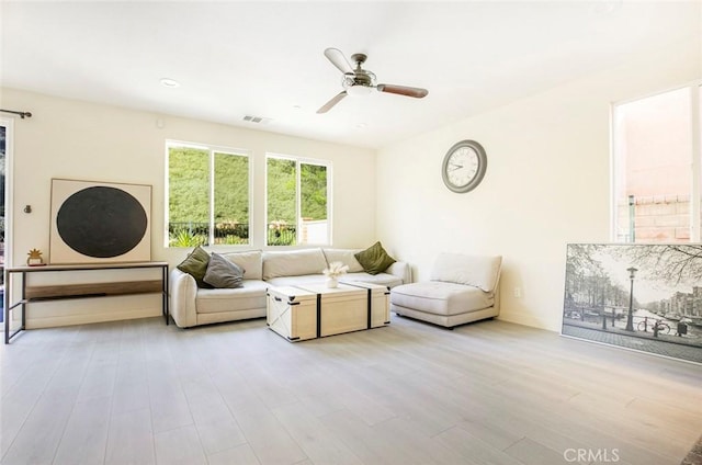 living area with ceiling fan, light wood finished floors, and visible vents