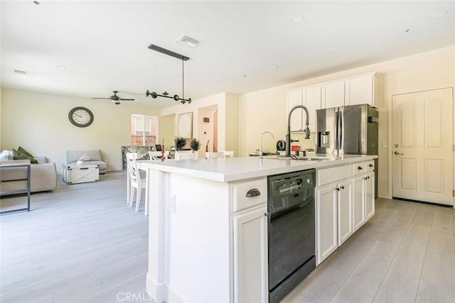 kitchen featuring black dishwasher, an island with sink, open floor plan, light countertops, and white cabinetry