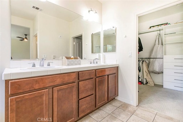 full bathroom with a walk in closet, double vanity, visible vents, a sink, and tile patterned flooring