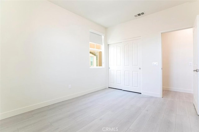 unfurnished bedroom with light wood-style floors, a closet, visible vents, and baseboards