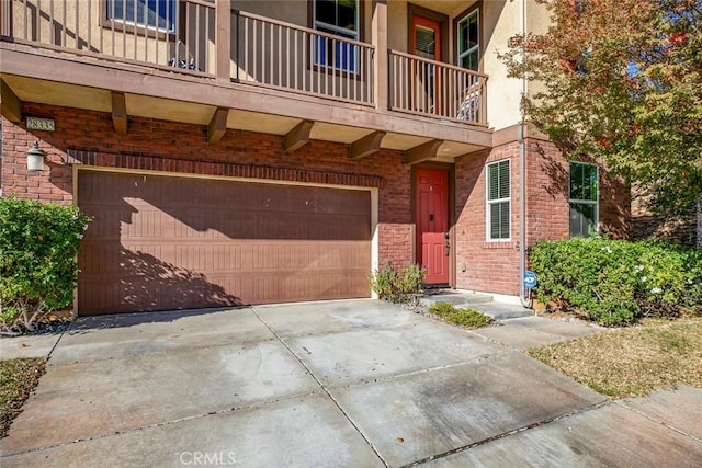 exterior space with a garage, concrete driveway, brick siding, and stucco siding