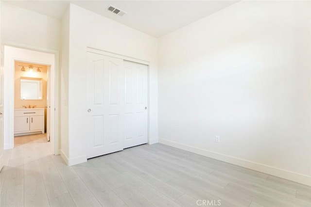 unfurnished bedroom featuring light wood-style floors, baseboards, and visible vents