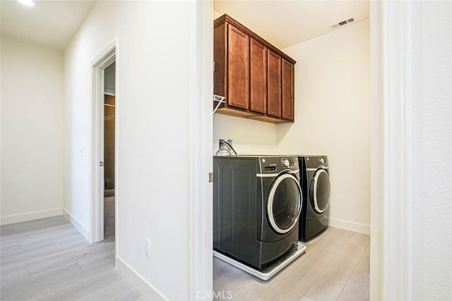 washroom featuring light wood-style flooring, visible vents, baseboards, independent washer and dryer, and cabinet space