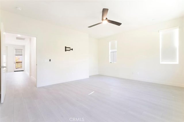 empty room featuring light wood finished floors, a ceiling fan, and baseboards