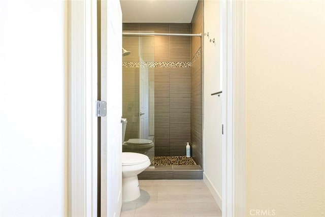 bathroom featuring tile patterned flooring, a shower stall, and toilet