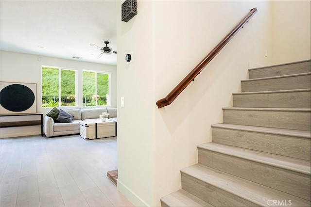 staircase with ceiling fan, wood finished floors, and visible vents