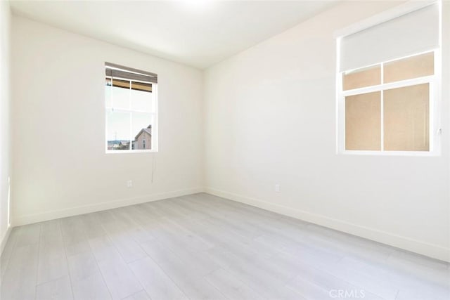 unfurnished room featuring baseboards and light wood finished floors