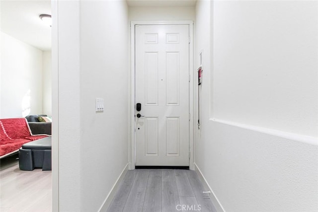 doorway featuring light wood-style flooring and baseboards