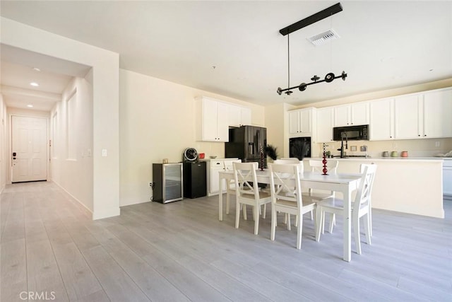 dining area with light wood-type flooring, wine cooler, visible vents, and recessed lighting