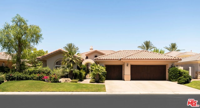 mediterranean / spanish house with a garage and a front yard