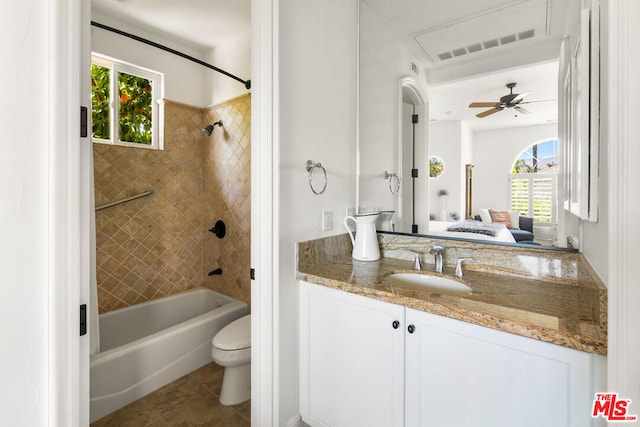 full bathroom with a wealth of natural light, toilet, ceiling fan, and tiled shower / bath