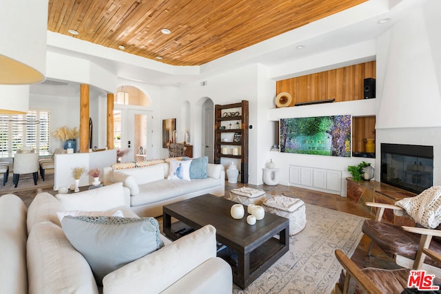 living room with a fireplace, wood ceiling, and light wood-type flooring