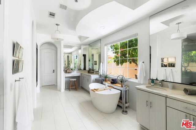 bathroom with a tub, tile patterned flooring, and vanity