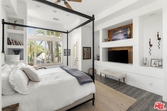 bedroom with a raised ceiling, ceiling fan, and dark hardwood / wood-style floors