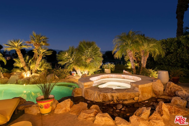 view of pool at twilight