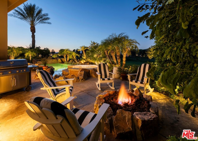 patio terrace at dusk with a fire pit and grilling area