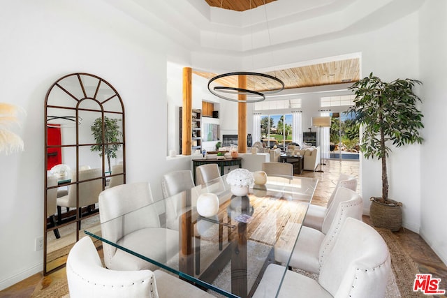 dining space with light hardwood / wood-style floors, wooden ceiling, a tray ceiling, and a chandelier