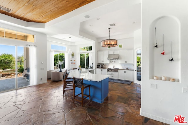 kitchen featuring white cabinetry, a center island, hanging light fixtures, stainless steel gas cooktop, and a breakfast bar