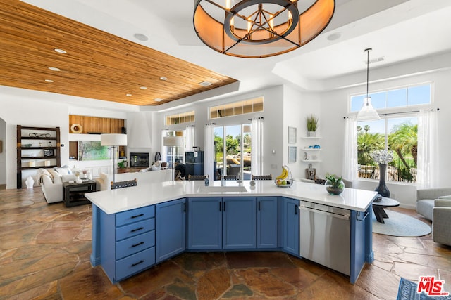 kitchen with sink, dishwasher, hanging light fixtures, blue cabinets, and a tray ceiling