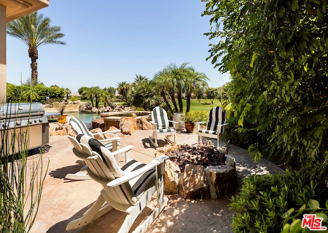 view of patio / terrace with a grill, a water view, and a fire pit