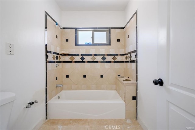 bathroom featuring tile patterned flooring, toilet, and tiled shower / bath