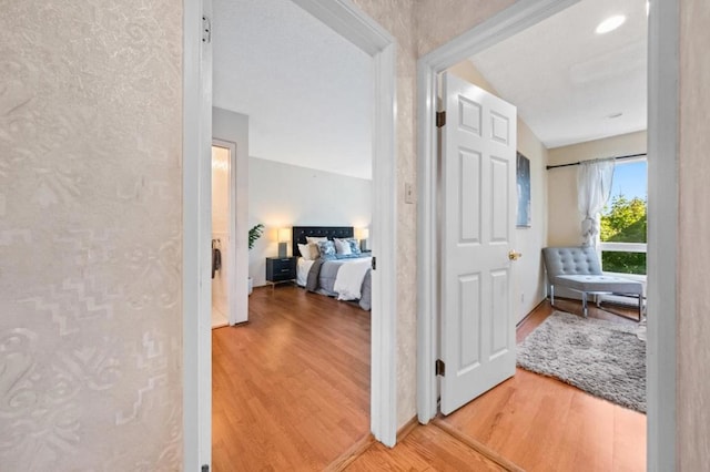 hallway with wood-type flooring and vaulted ceiling