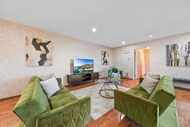 living room featuring wood-type flooring and a textured ceiling