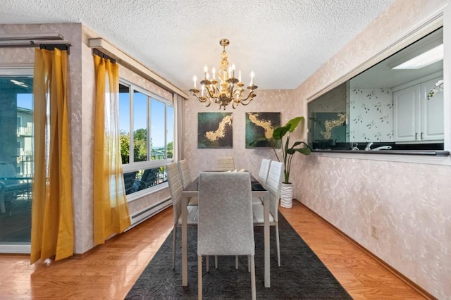 dining room featuring baseboard heating, a textured ceiling, a chandelier, and light hardwood / wood-style flooring