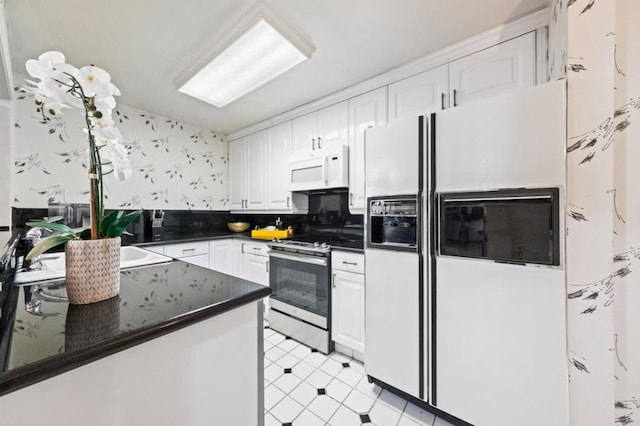 kitchen featuring dark stone counters, white cabinets, white appliances, and kitchen peninsula