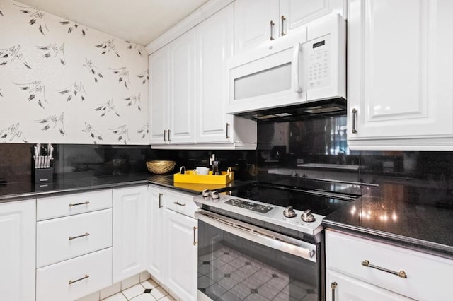 kitchen featuring stainless steel range with electric stovetop, light tile patterned floors, decorative backsplash, and white cabinets