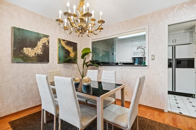 dining space with hardwood / wood-style flooring, a textured ceiling, and a notable chandelier