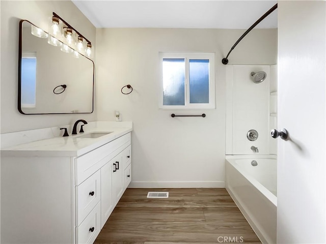 bathroom with hardwood / wood-style flooring, vanity, and shower / washtub combination