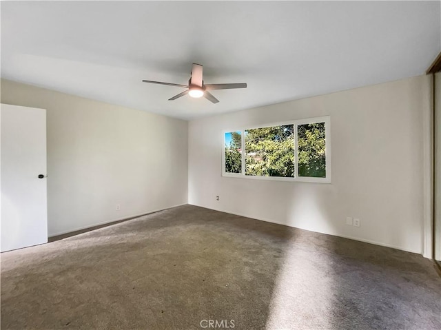 spare room featuring dark colored carpet and ceiling fan