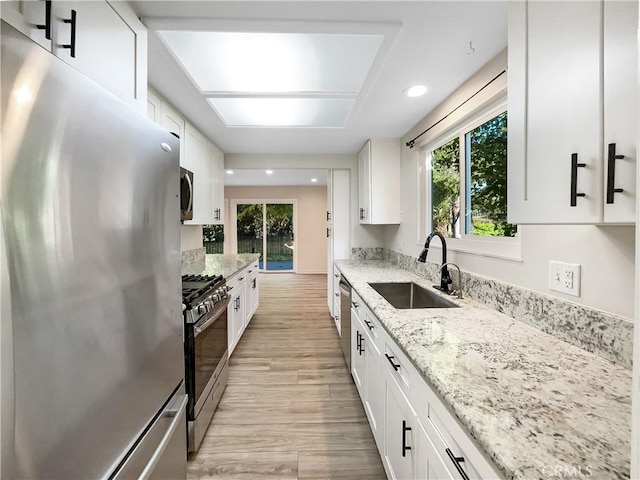 kitchen with white cabinetry, sink, stainless steel appliances, and light hardwood / wood-style flooring