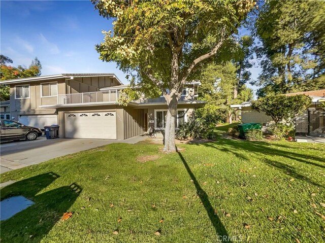 view of front of home with a balcony, a front yard, and a garage