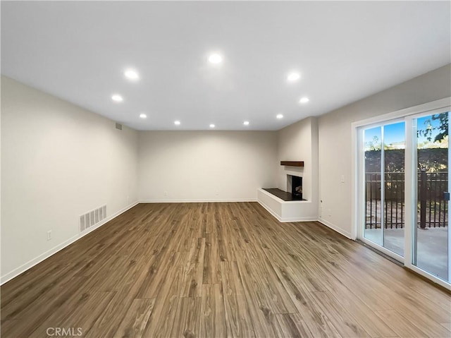 unfurnished living room featuring a multi sided fireplace and hardwood / wood-style flooring