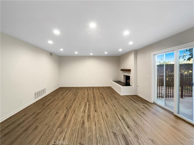 unfurnished living room featuring a multi sided fireplace and hardwood / wood-style floors