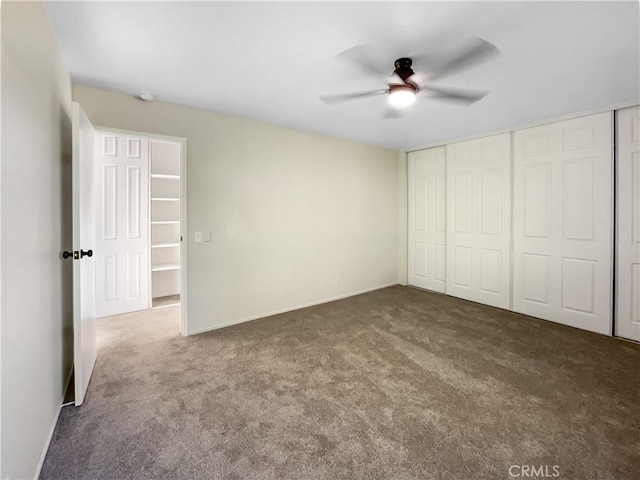 unfurnished bedroom featuring a closet, dark carpet, and ceiling fan