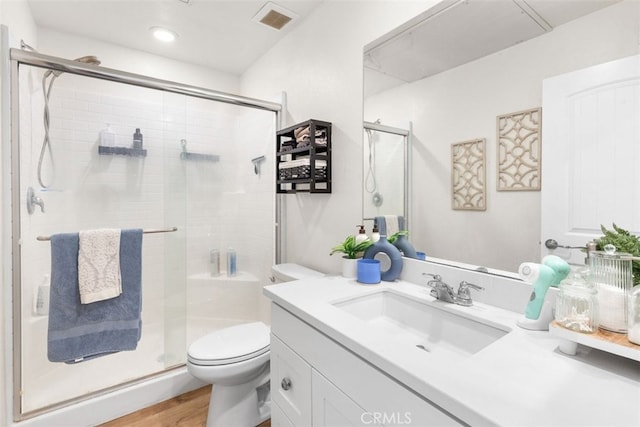 bathroom featuring hardwood / wood-style floors, vanity, toilet, and a shower with shower door