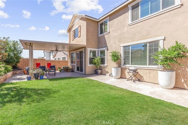 rear view of house featuring a lawn and a patio