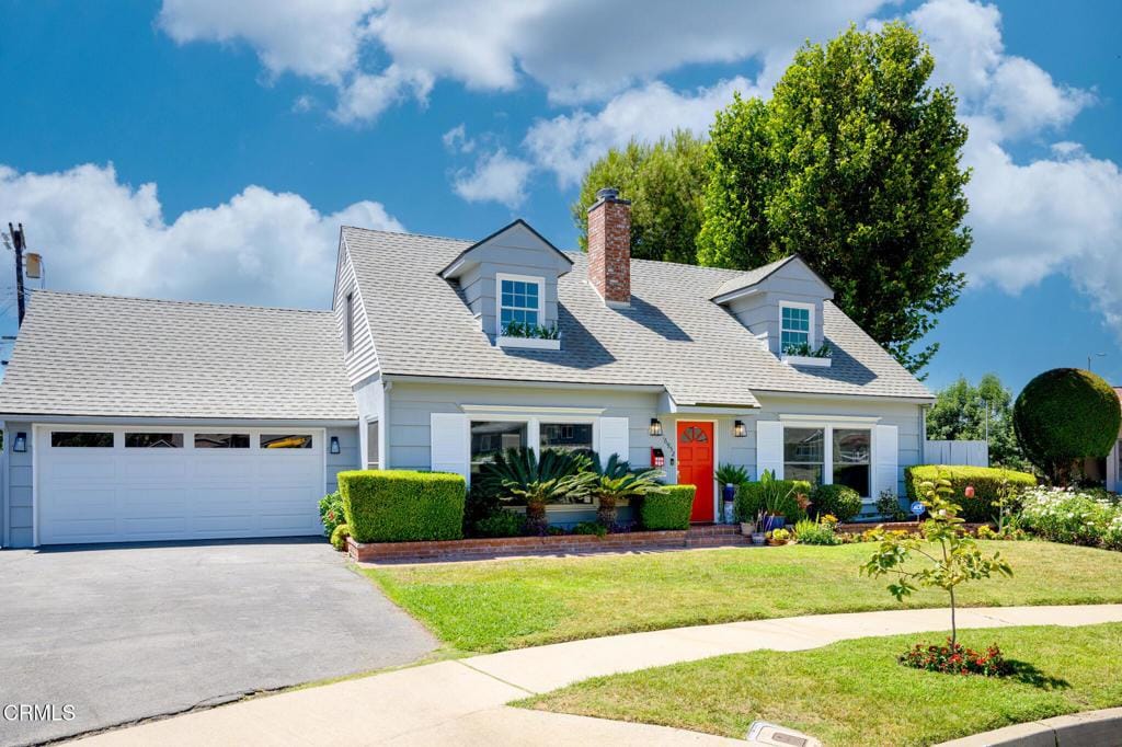 cape cod home featuring a front lawn and a garage