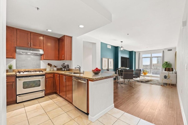 kitchen featuring sink, light hardwood / wood-style flooring, stainless steel dishwasher, kitchen peninsula, and white stove