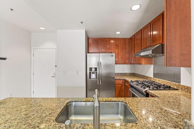 kitchen with light stone counters, sink, kitchen peninsula, and stainless steel appliances